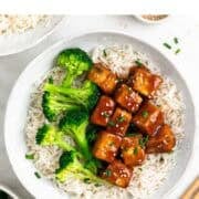 Teriyaki tofu bowl served over white rice and garnished with fresh chives.