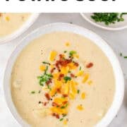 Vegan potato soup served in two bowls with the ingredients displayed around them.