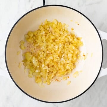 Sautéed onion and garlic cooked in a pot until golden and fragrant.