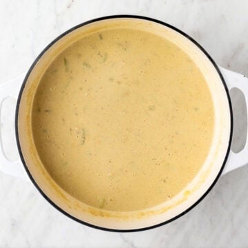 Cooked vegan potato soup with nutritional yeast and lemon juice stirred in the pot.