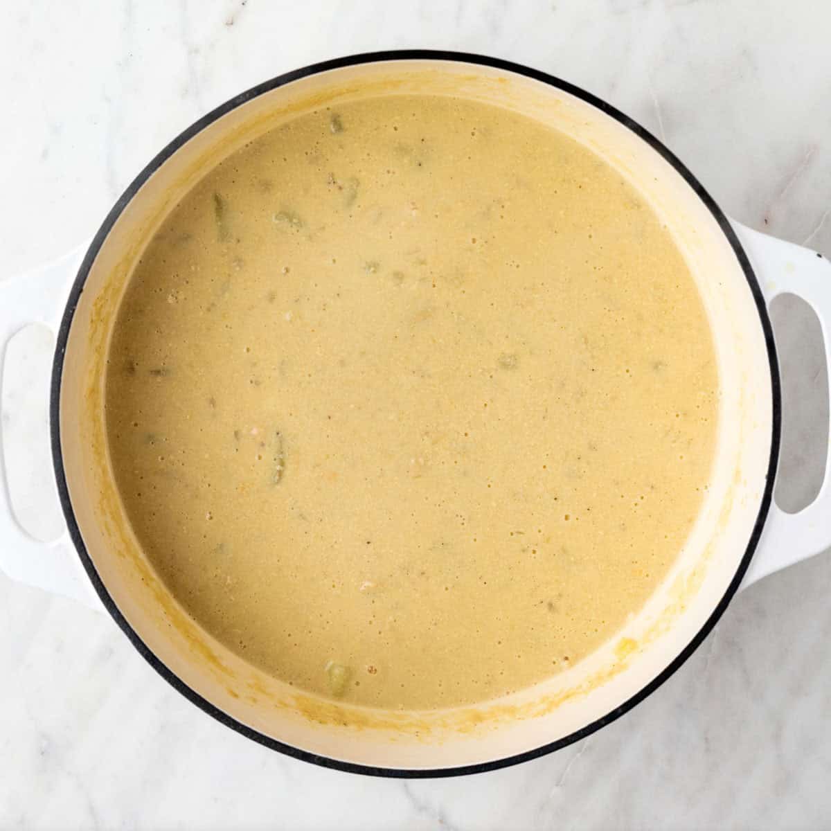 Cooked vegan potato soup with nutritional yeast and lemon juice stirred in the pot.