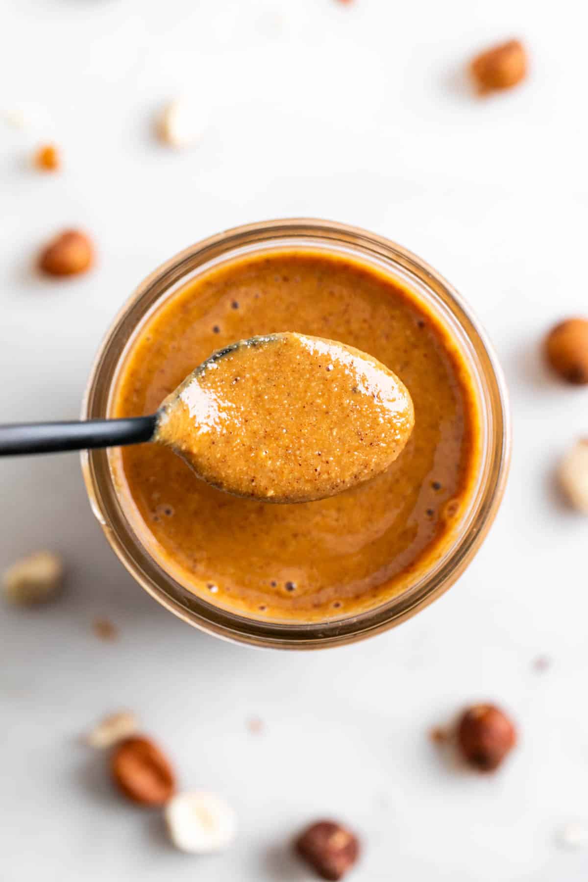 Spoon with hazelnut butter held over a jar