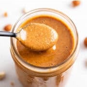 Scooping hazelnut butter from a jar with a spoon.