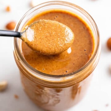 Spoon scooping out hazelnut butter from a jar.
