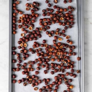 Roasted hazelnuts on a lined baking sheet.