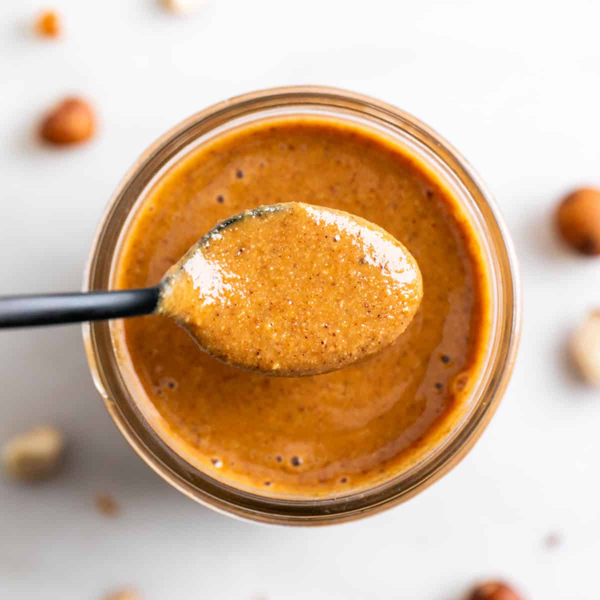 Spoonful of hazelnut butter over a jar.
