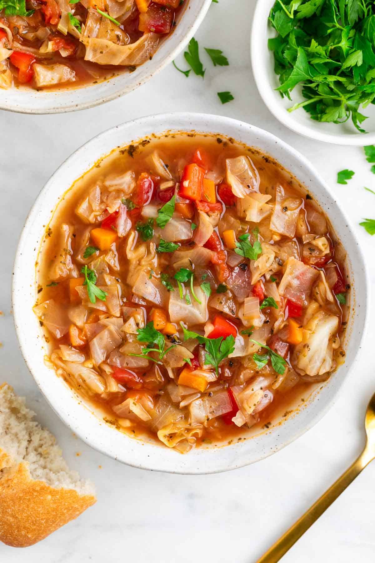 Bowls of vegan cabbage soup served with bread on the side.