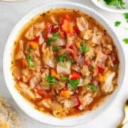 Vegan cabbage soup served with a piece of bread.