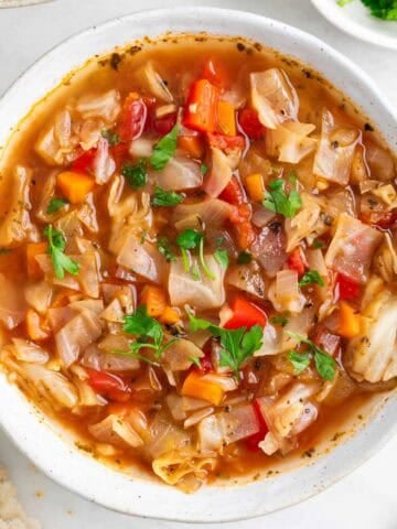 Vegan cabbage soup served with a piece of bread.