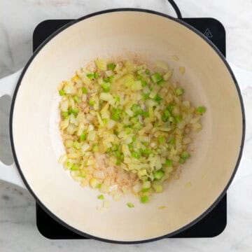 Onion and celery sautéed in a pot.