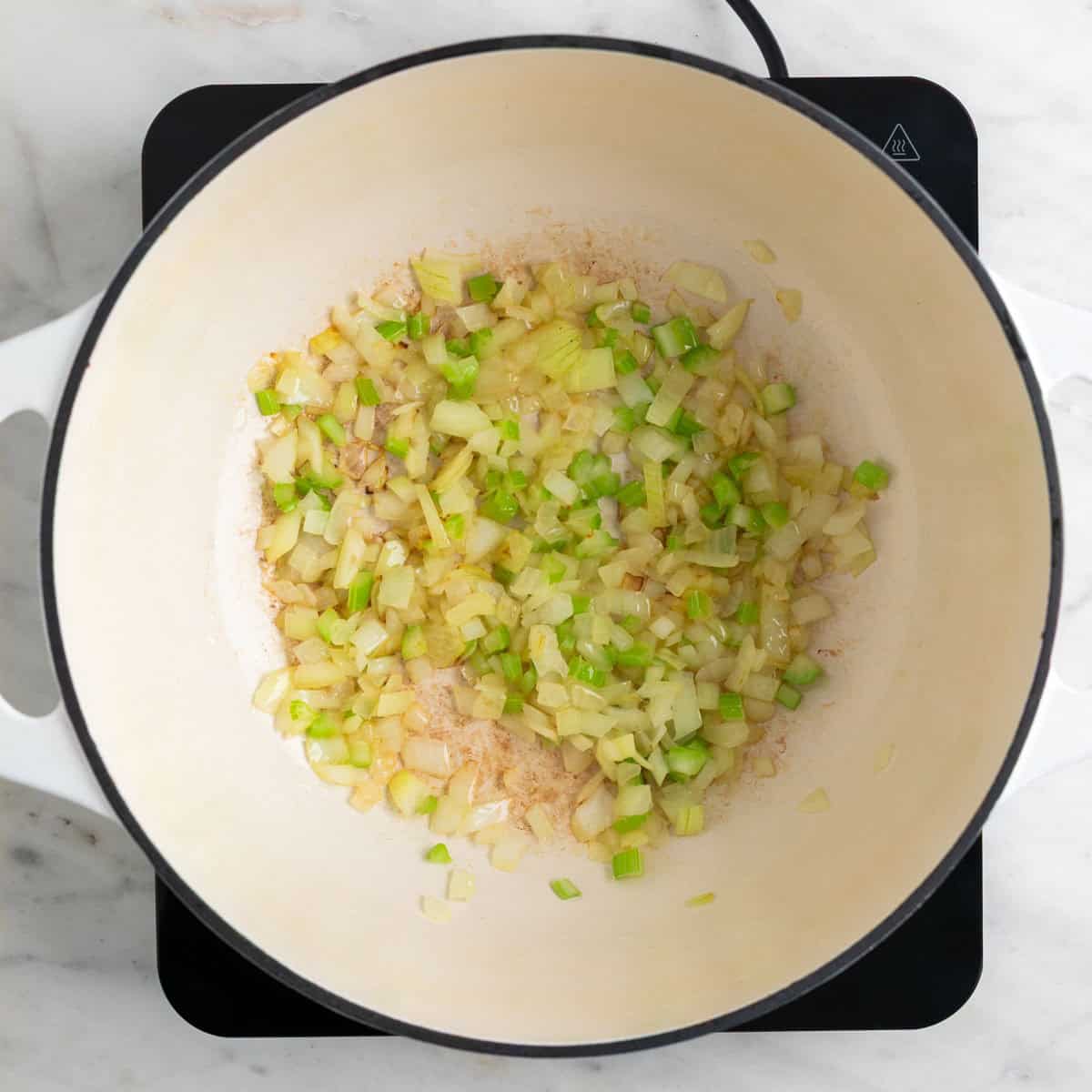 Onion and celery sautéed in a pot.