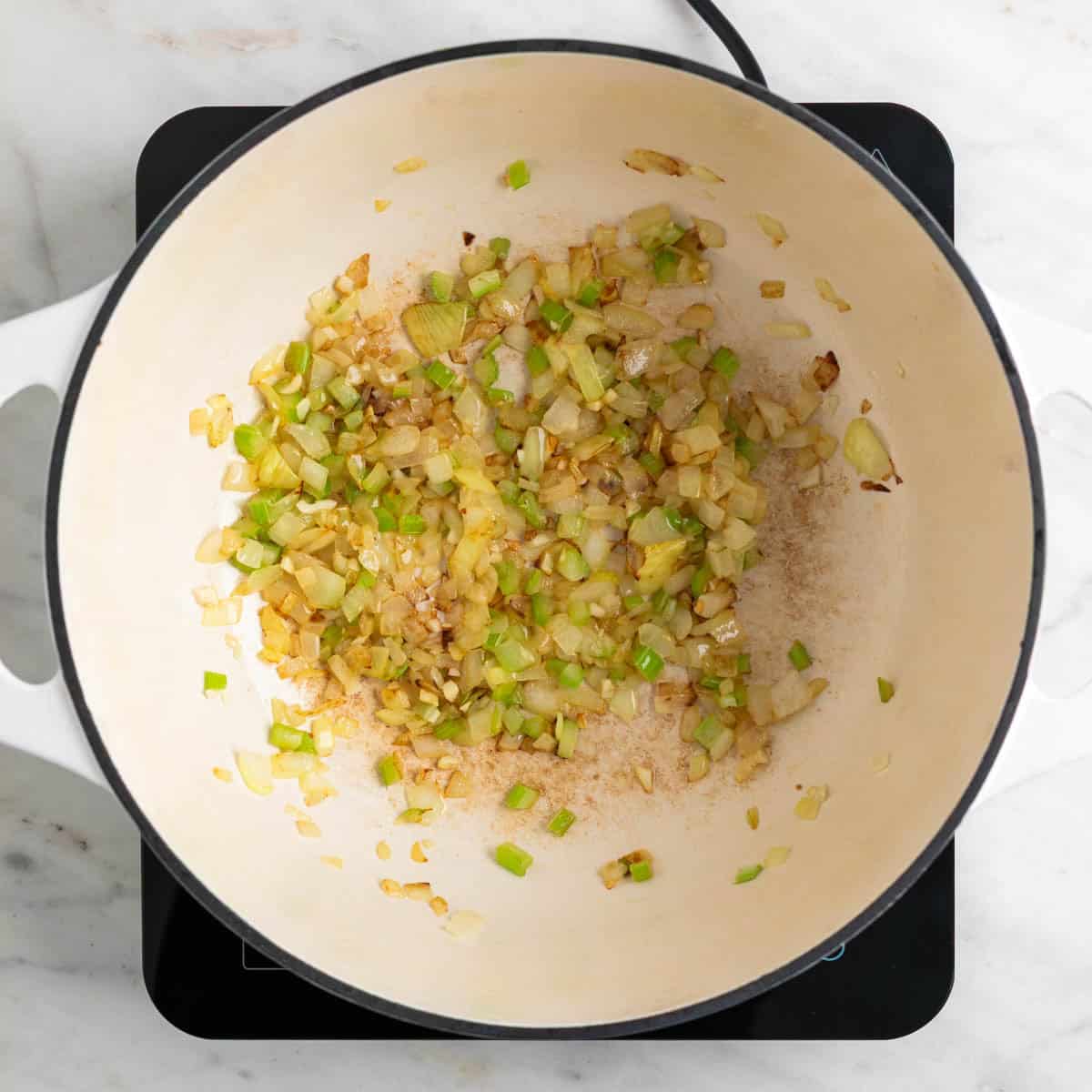 Onion, celery, and garlic sautéed in a pot.