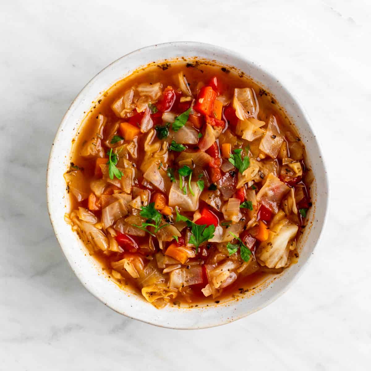 Vegan cabbage soup served in a bowl with fresh parsley on top