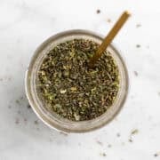 Jar of homemade Italian seasoning with a spoon.