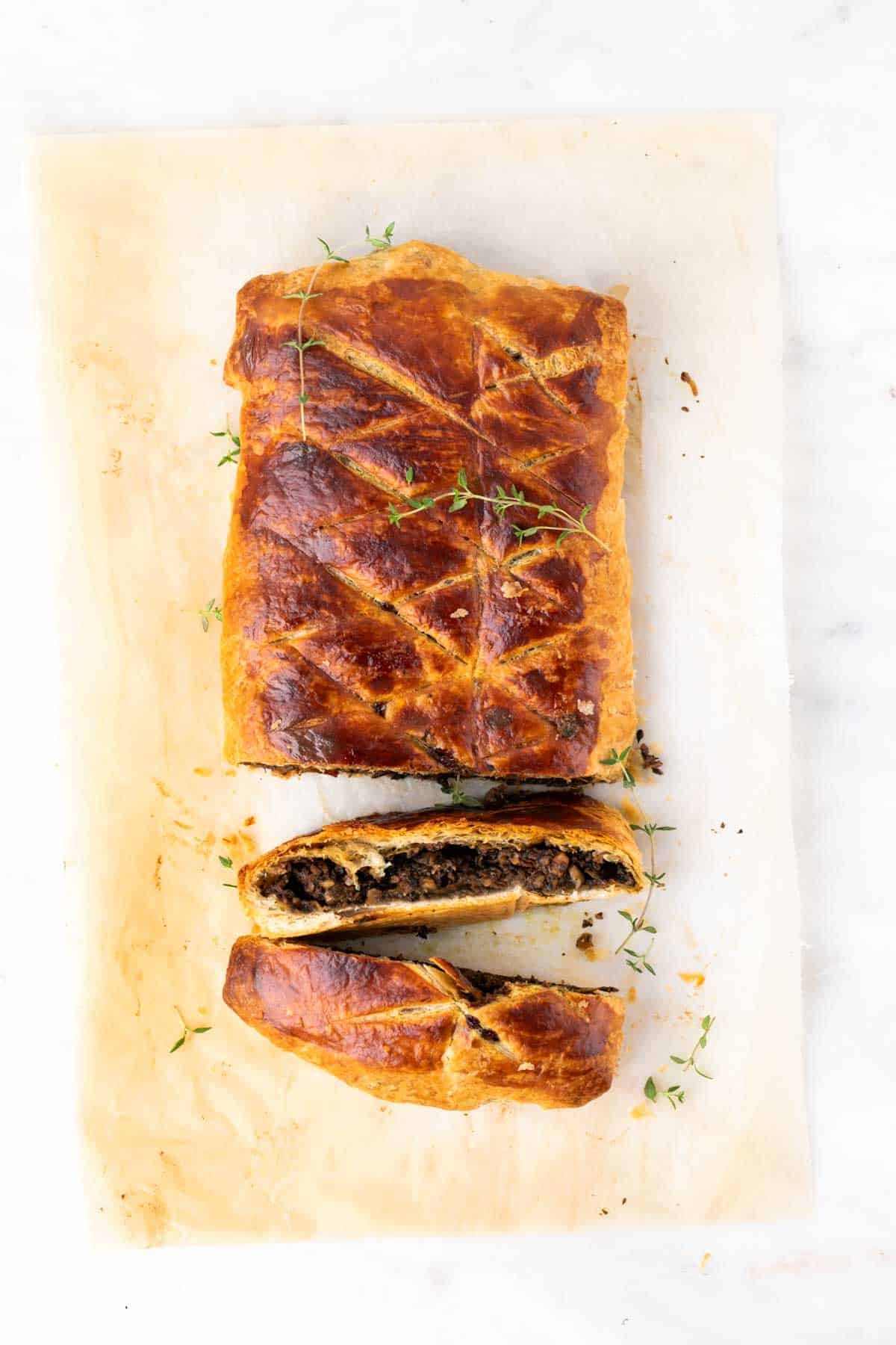 Baked mushroom wellington with two slices cut and the rest whole.