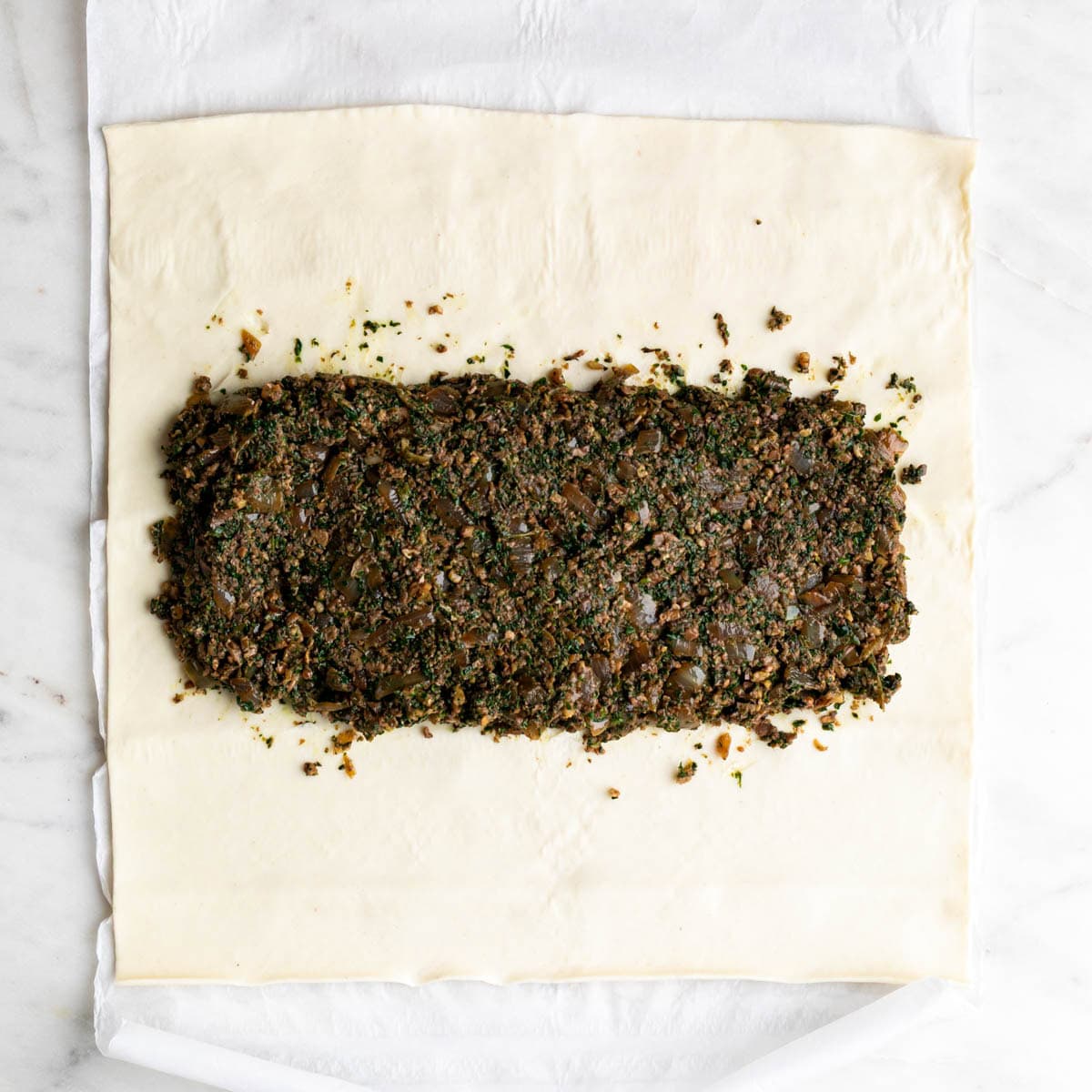 Mushroom filling spread down the center of puff pastry.