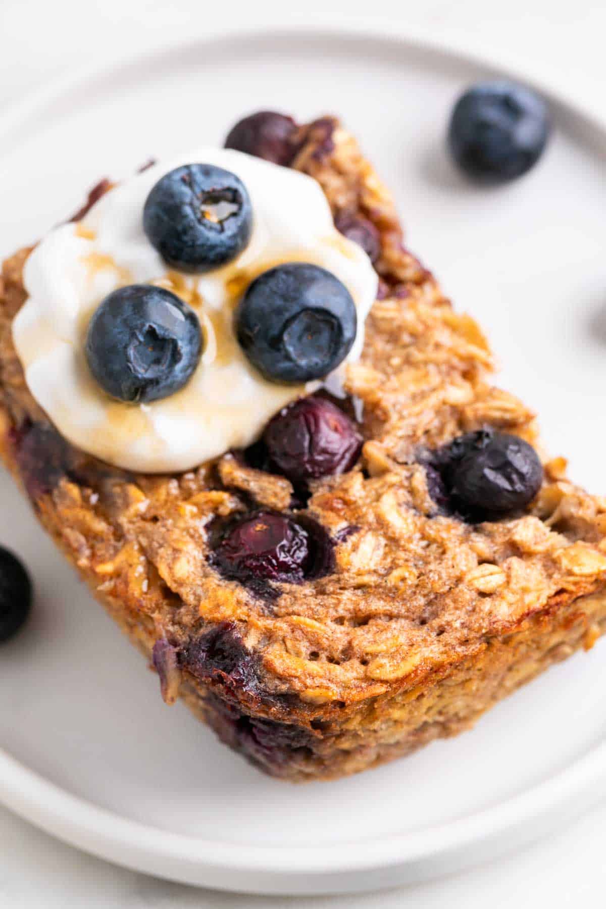 Slice of vegan baked oatmeal served on a plate with blueberries.