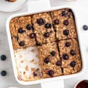 Baking dish with vegan baked oatmeal cut into squares, with one piece missing.