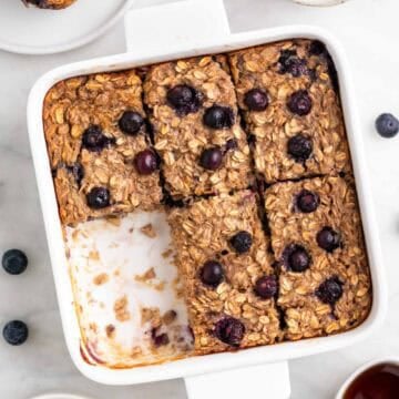 Baking dish with vegan baked oatmeal cut into squares, with one piece missing.