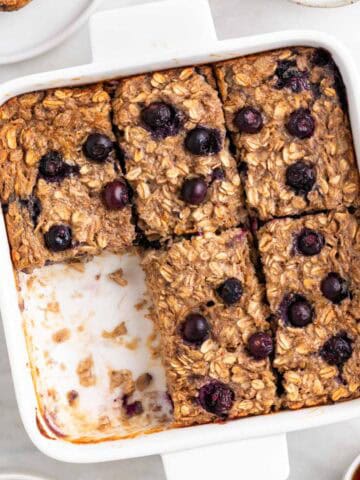 Baking dish with vegan baked oatmeal cut into squares, with one piece missing.