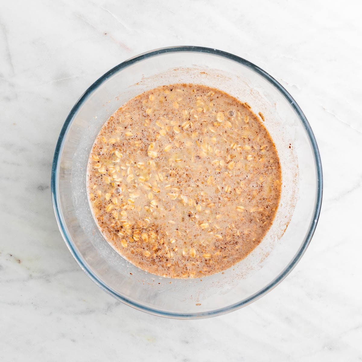 Vegan baked oatmeal ingredients mixed in a large bowl, excluding the blueberries.
