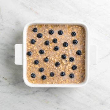 Vegan baked oatmeal mixture in a baking dish topped with blueberries.