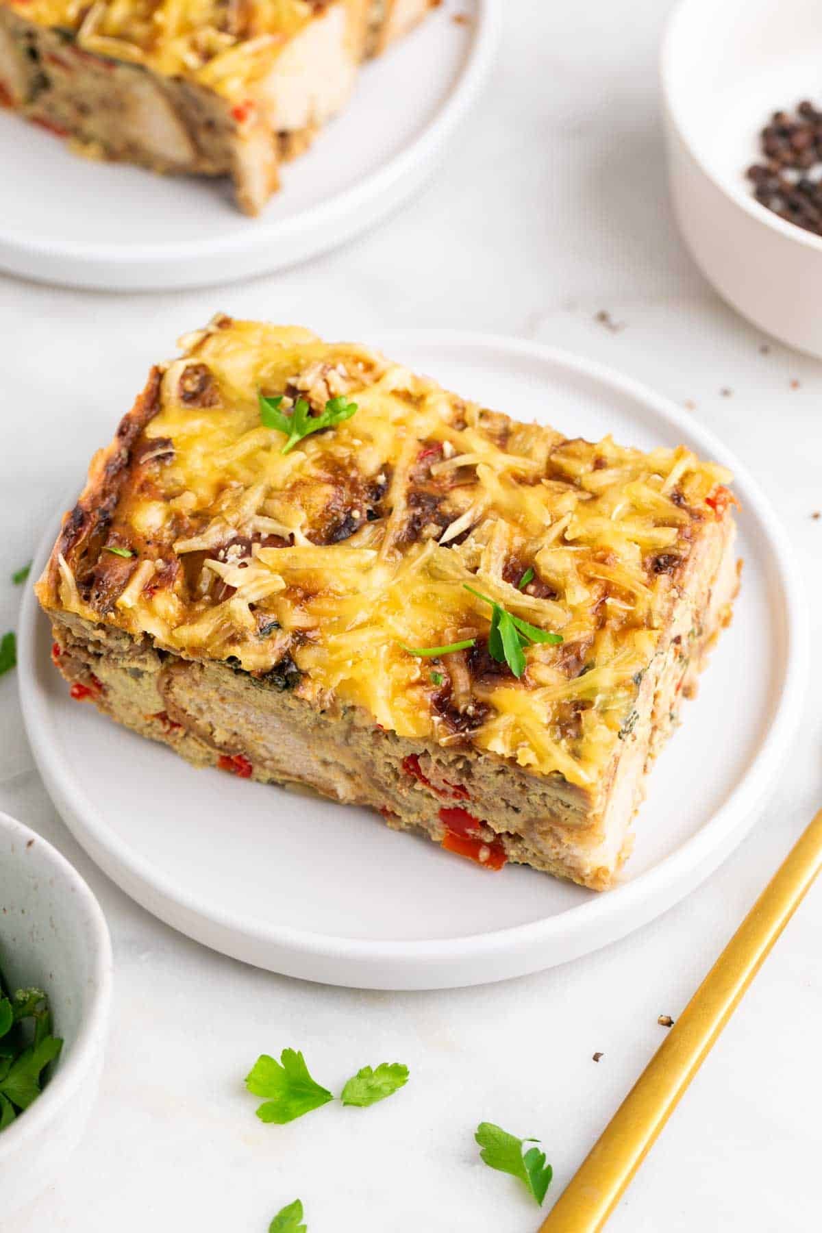 Slice of vegan breakfast casserole on a plate garnished with parsley.