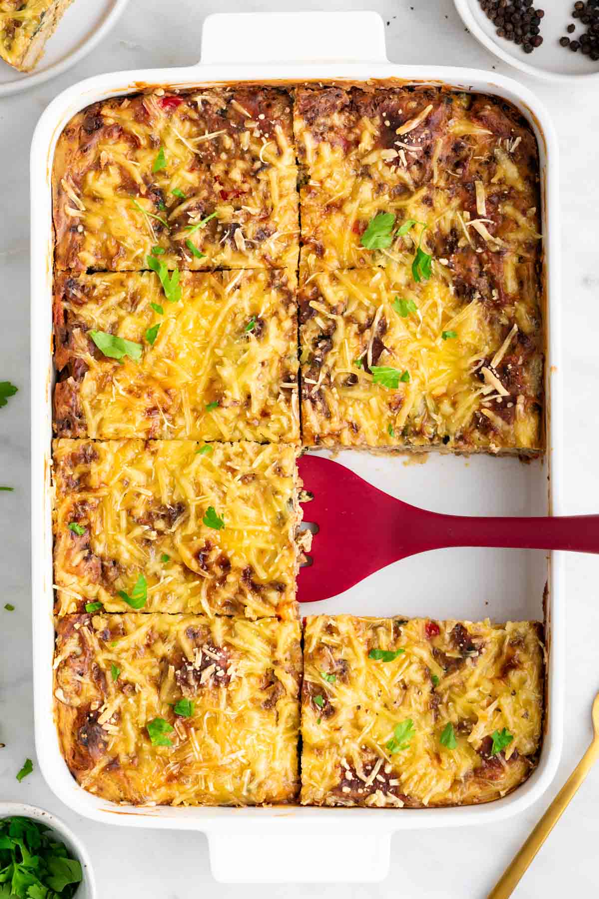 Vegan breakfast casserole cut into squares with a spatula.