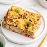 Slice of vegan breakfast casserole on a plate garnished with parsley.