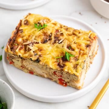 Slice of vegan breakfast casserole on a plate garnished with parsley.