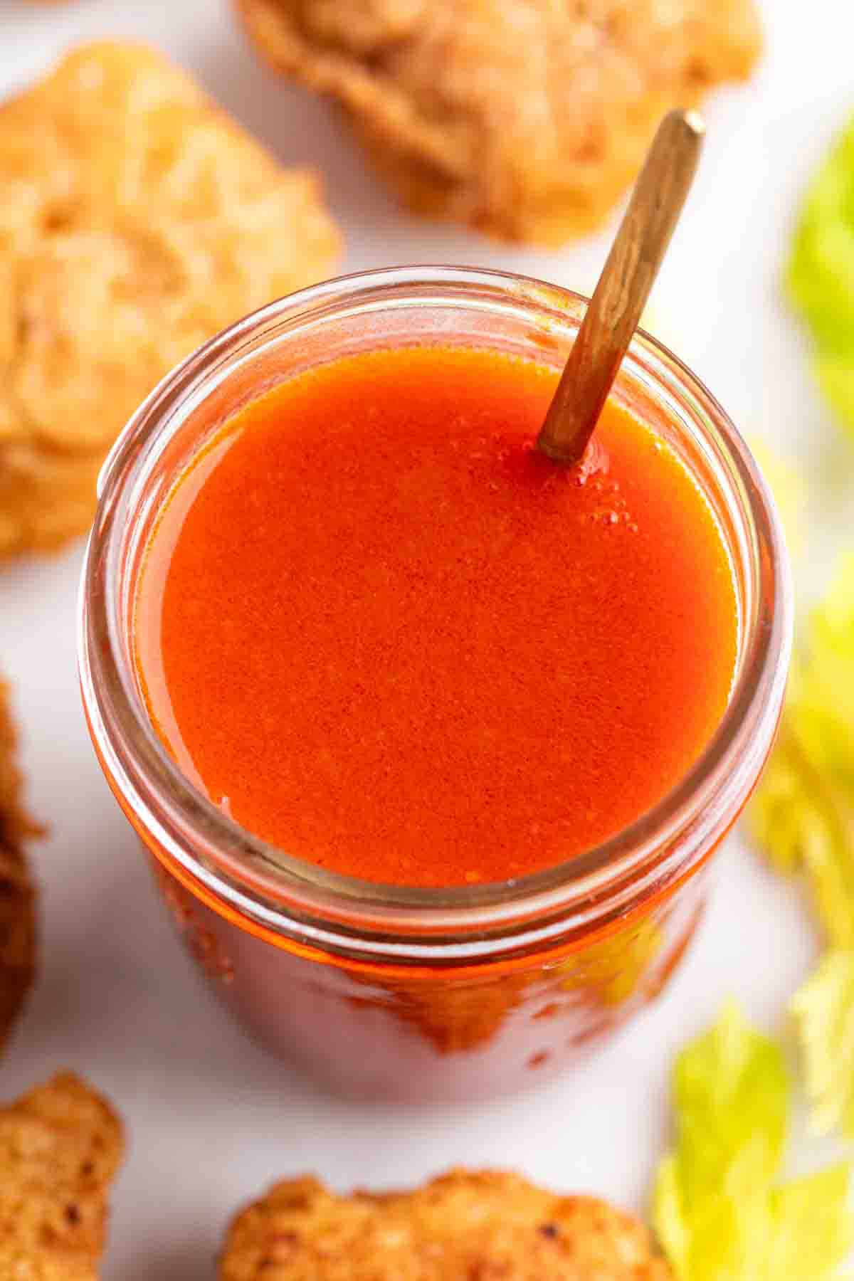 Buffalo sauce served with tofu wings and celery sticks.
