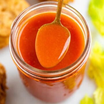 Vegan buffalo sauce being spooned from a jar.