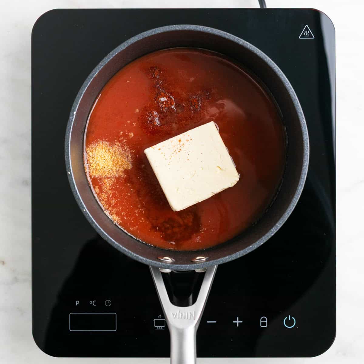 Ingredients for vegan buffalo sauce in a saucepan.