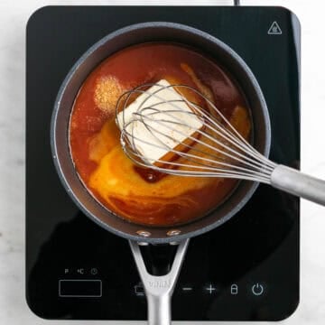 Vegan buffalo sauce ingredients being whisked in a saucepan.