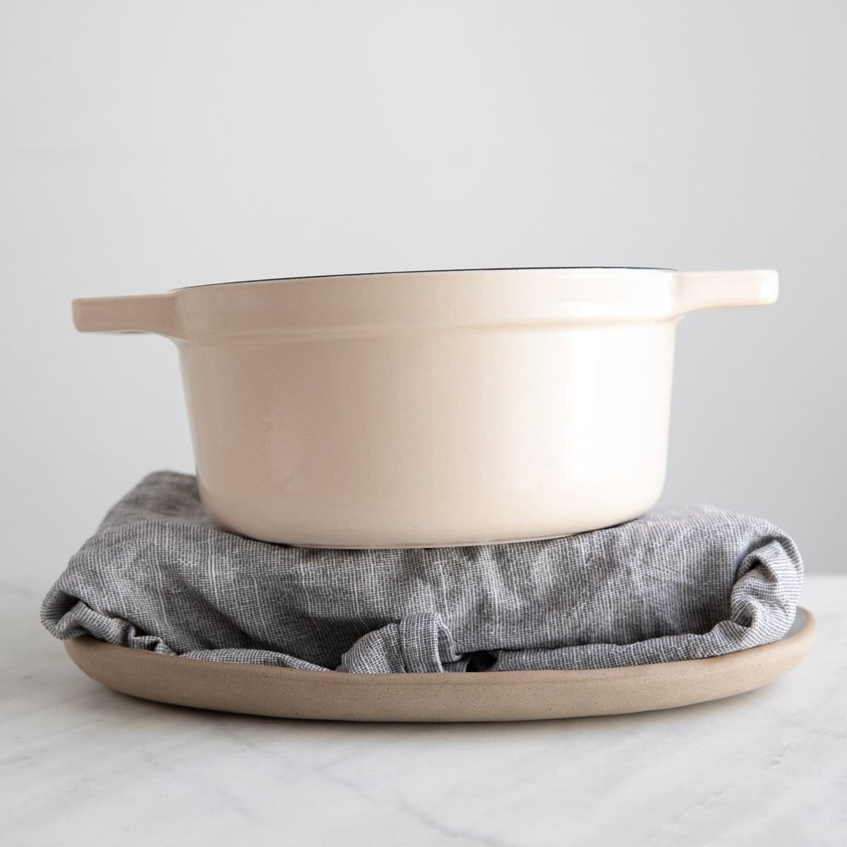 Tofu wrapped in a clean towel on a plate with a pot on top.