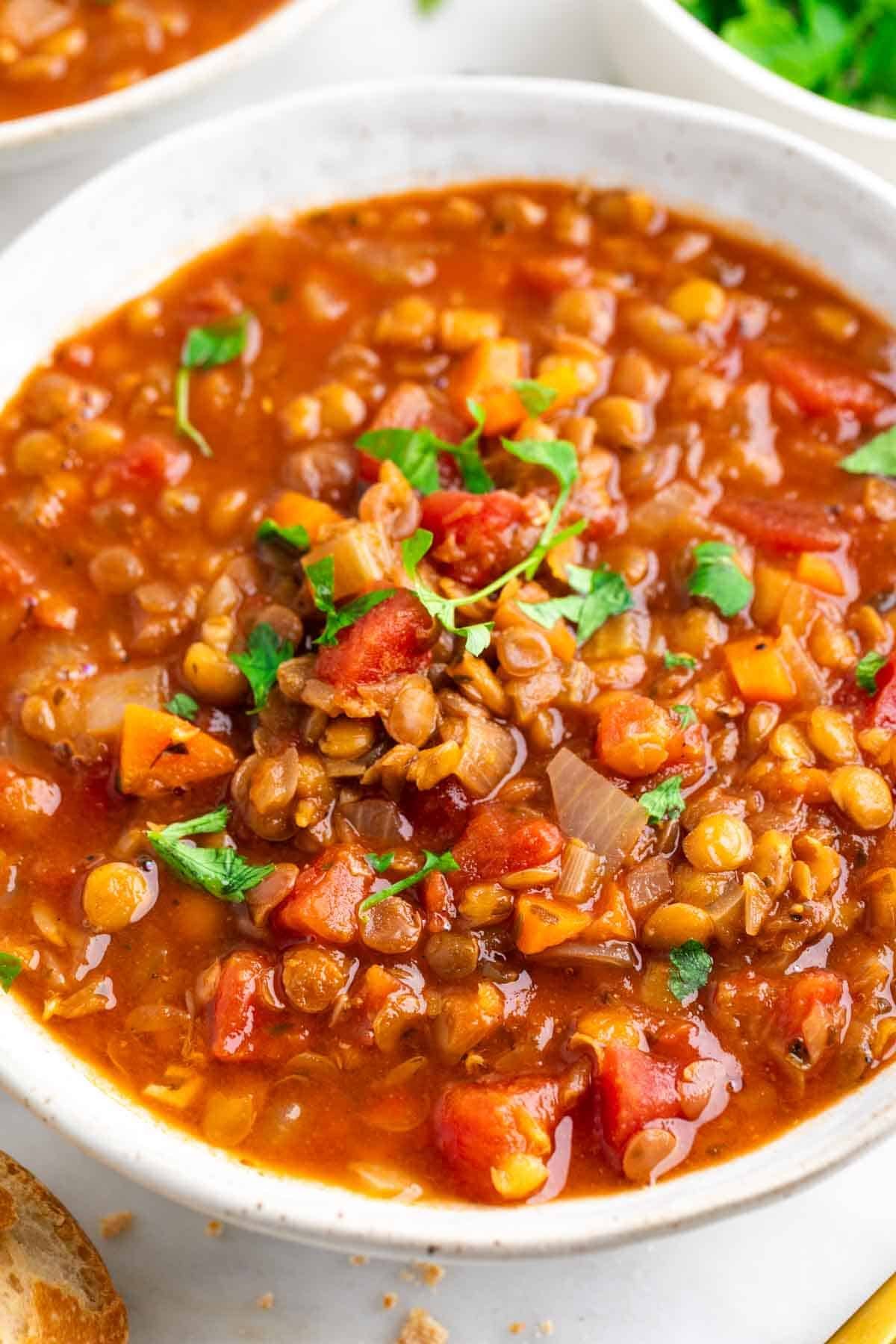 Vegan lentil soup in a bowl garnished with parsley.