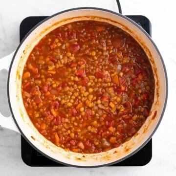 Cooked vegan lentil soup in a large pot before adding salt and black pepper.