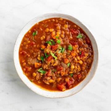 Vegan lentil soup served in a bowl and topped with fresh parsley.