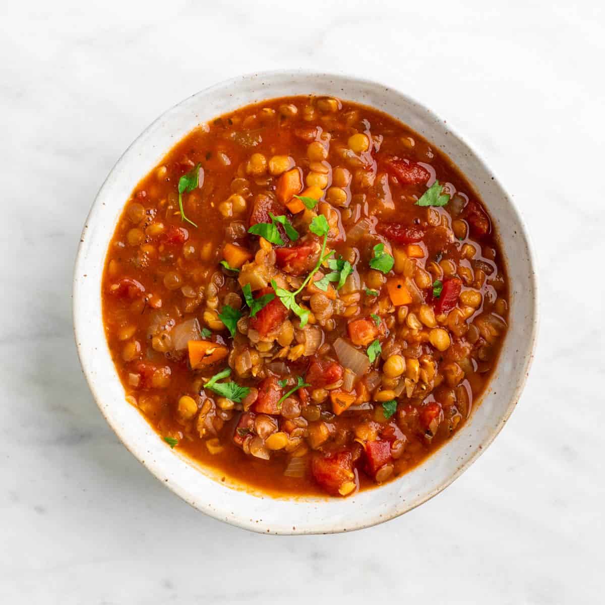 Vegan lentil soup served in a bowl and topped with fresh parsley.