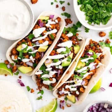 Homemade tofu tacos with avocado, red onion, cilantro, and vegan sour cream, served with extra toppings on the side.