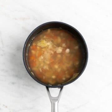 Cooked cashews and carrots in a saucepan.