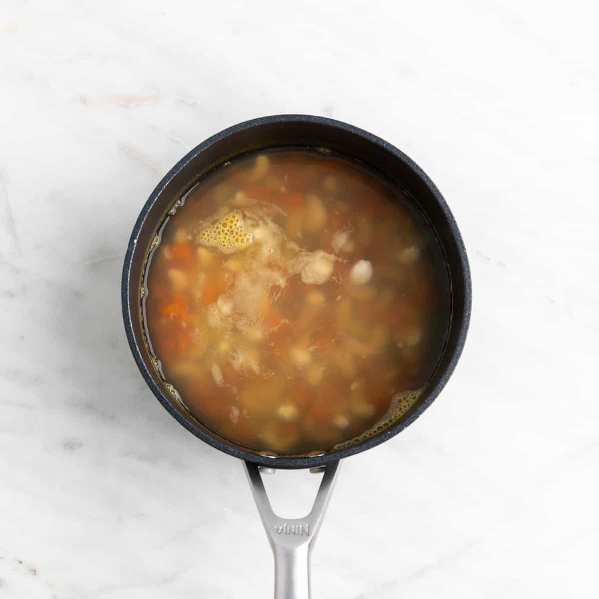 Cooked cashews and carrots in a saucepan.