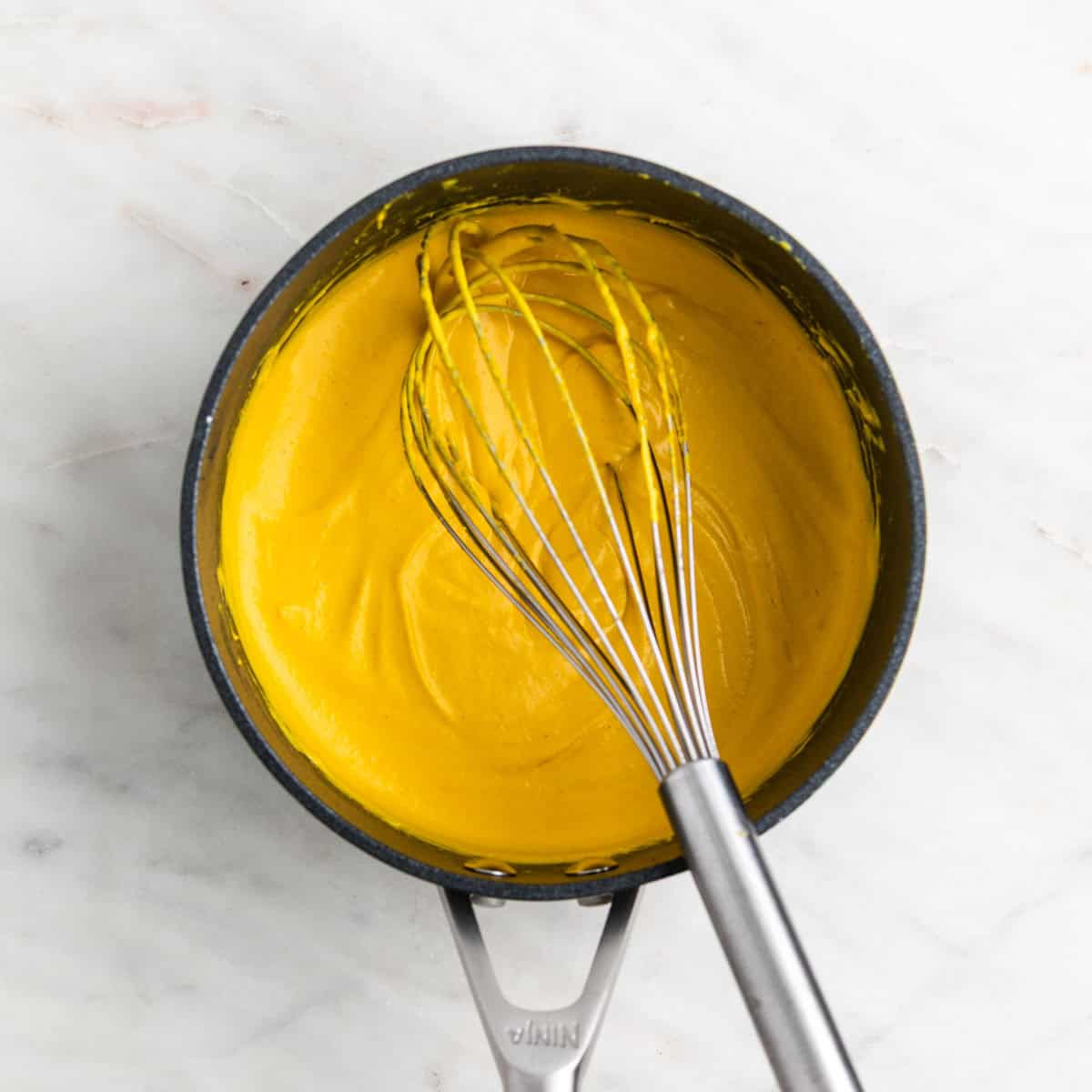 Vegan cheddar cheese spread in a saucepan after cooking.