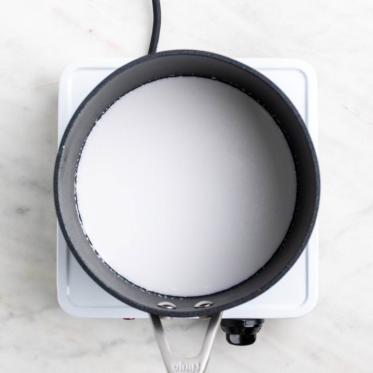 Hot coconut milk in a saucepan.