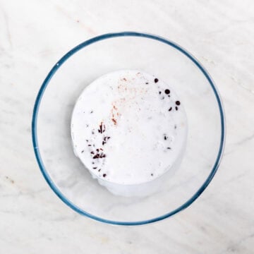 Hot coconut milk poured over chocolate chips in a bowl.