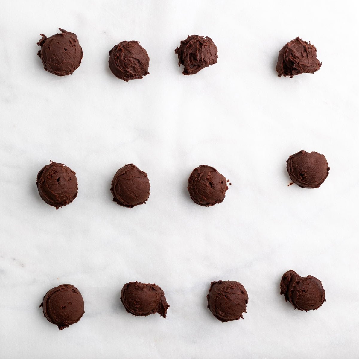 Scooped chocolate ganache on parchment paper.