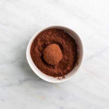 Chocolate truffle being rolled in cocoa powder.