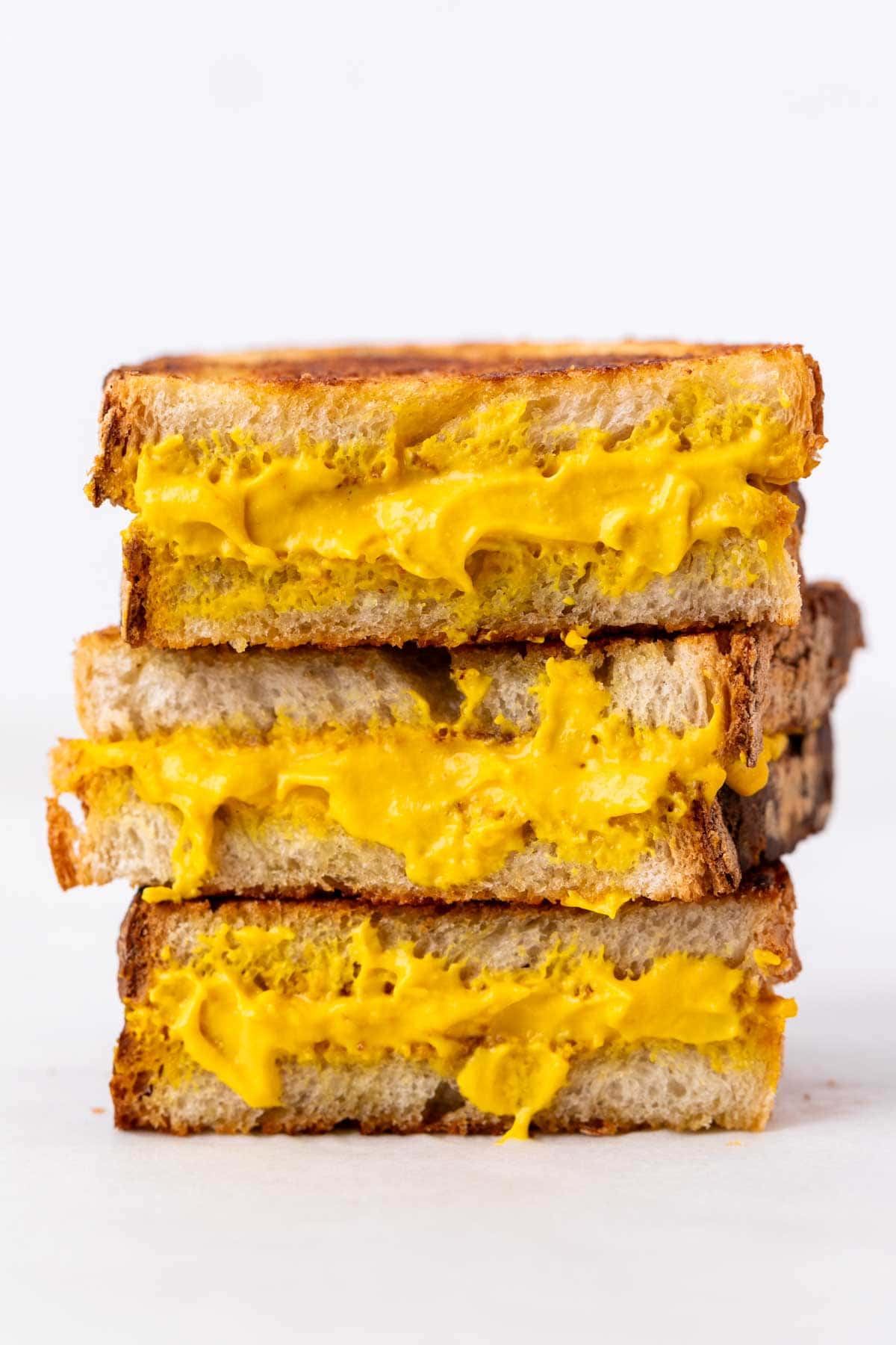 Crispy vegan grilled cheese halves stacked together.