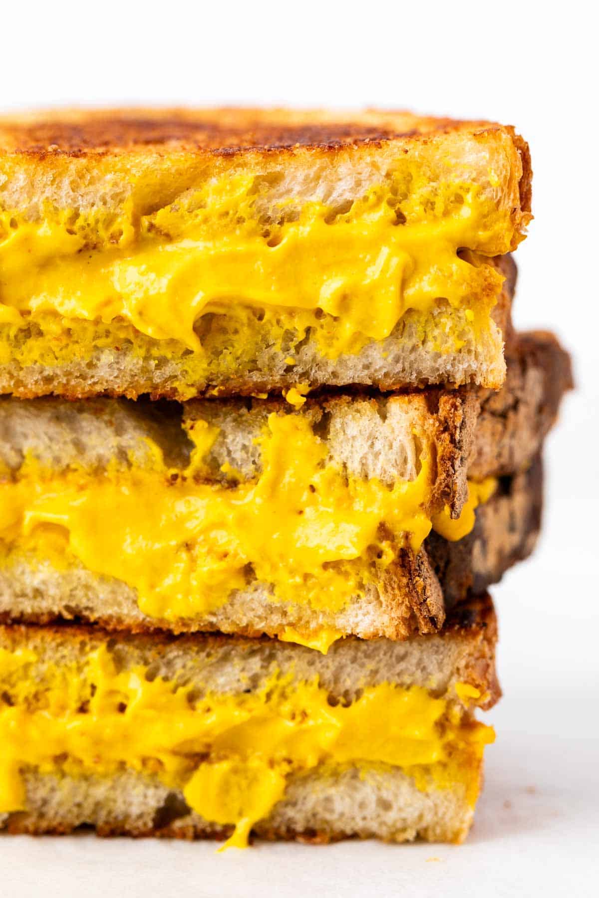 Crispy vegan grilled cheese halves stacked together.