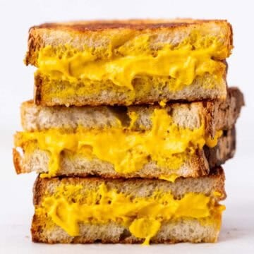 Three halves of a vegan grilled cheese sandwich stacked on top of each other.